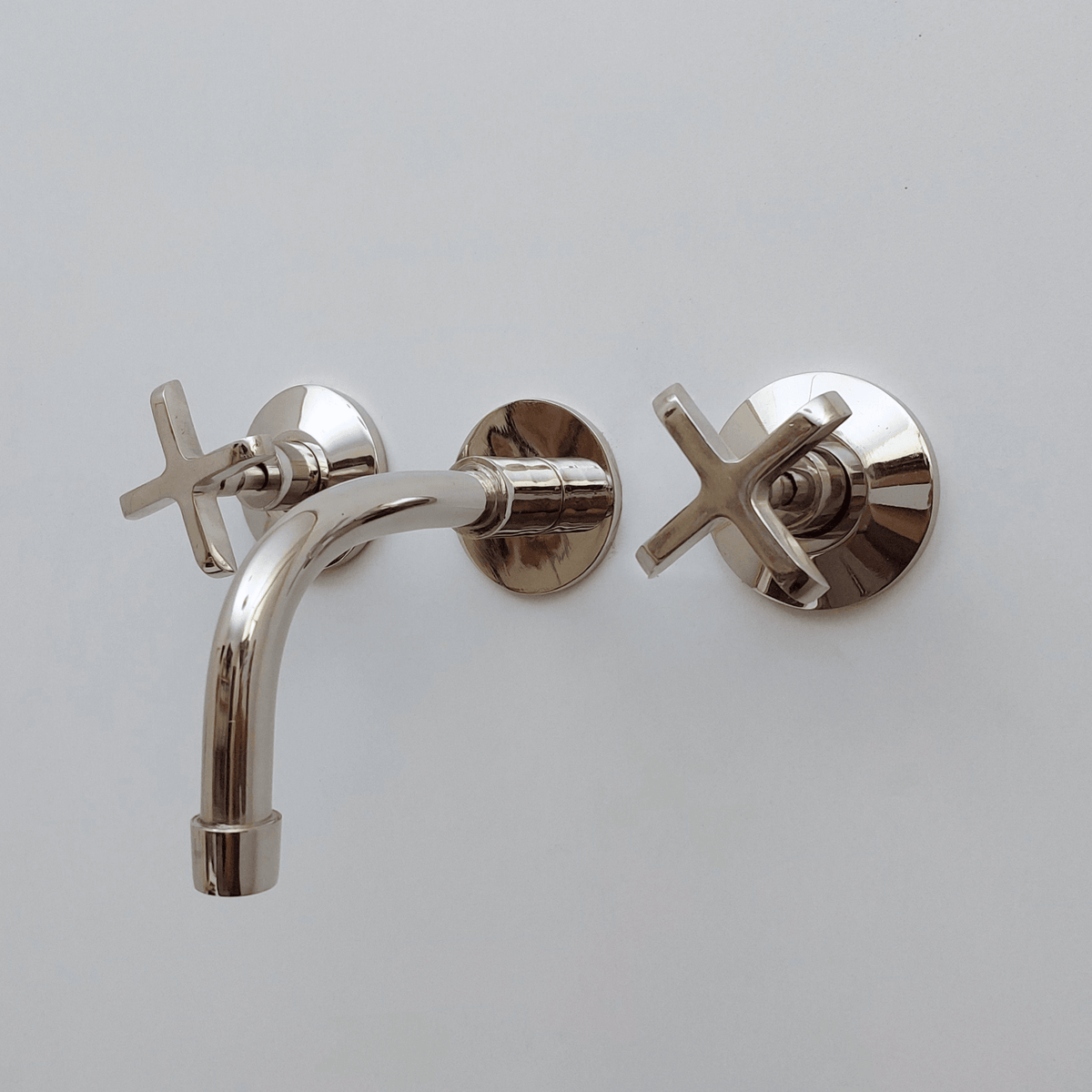 Polished nickel wall-mount bathroom faucet with reflective finish